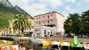 A waterfront hotel with boats docked, a palm tree, and a mountain in the background.
