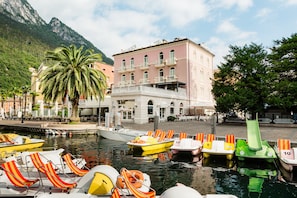 A waterfront hotel with boats docked, a palm tree, and a mountain in the background.