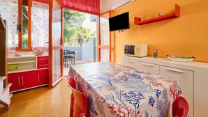 Ein Zimmer mit Esstisch, gedecktem Tisch, einem an der Wand befestigten Fernseher und einem roten Regal mit Dekoration.