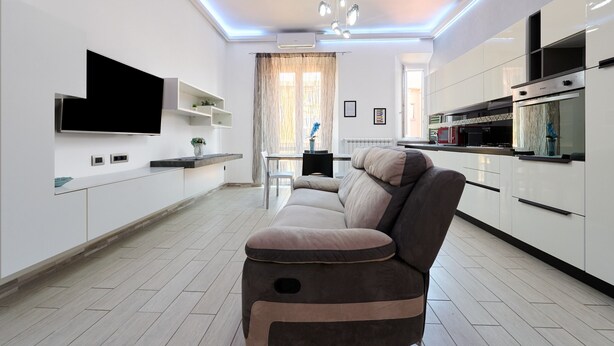 A modern kitchen with white cabinets, a built-in oven, and a flat-screen TV mounted on the wall. - Apartment 'Holy Days' with Balcony, Wi-Fi and Air Conditioning (Piombino)