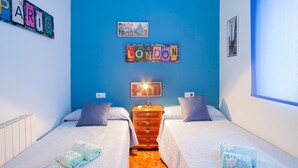 Habitación de hotel con dos camas, un aparador, una lámpara y una pared decorada con el nombre de la ciudad.