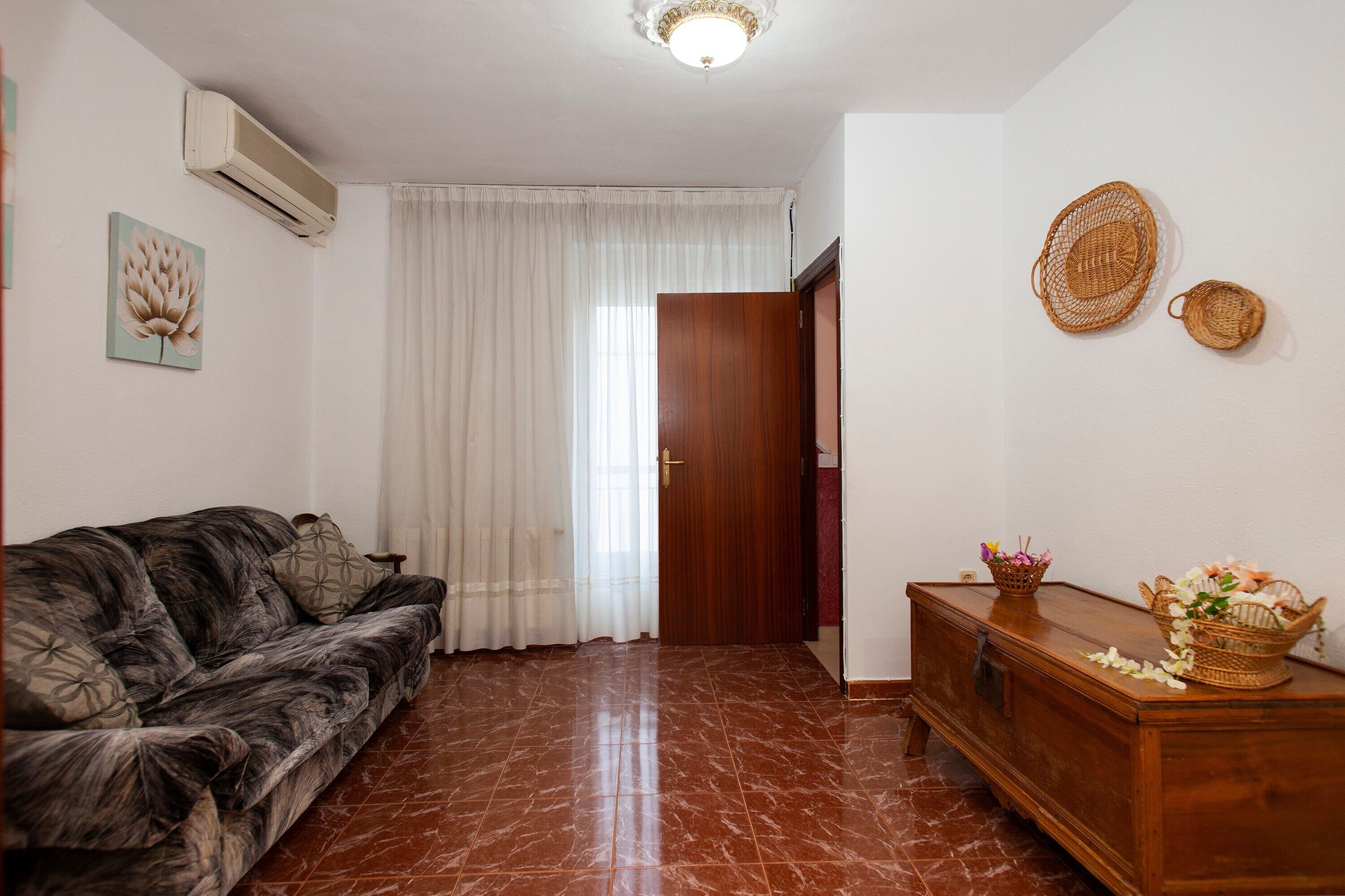 Una sala de estar con un sofá, un aparador de madera y una puerta que da a otra habitación.