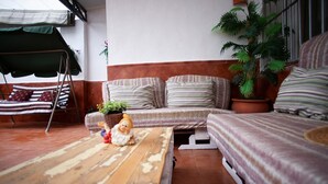 Una habitación acogedora con sofá, una mesita, una silla colgante y una planta en maceta.