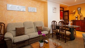 Una sala de estar con sofá, mesa de centro y comedor con sillas y una mesa.
