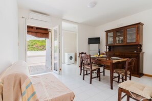 A room with a bed, a dining table with chairs, a wooden cabinet, and a washing machine.