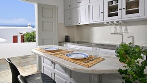 A kitchen with white cabinets, a bar counter, and a view of the sea. - Apartment 'Casa D'irene Mykonian Residence' with Sea View, Wi-Fi and Air Conditioning (Mýkonos City)