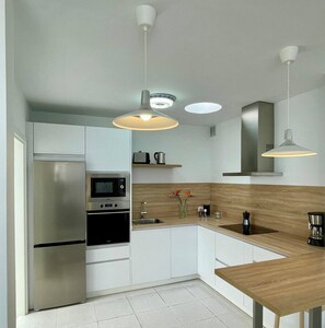 Una cocina moderna con electrodomésticos de acero inoxidable, detalles de madera e iluminación colgante.