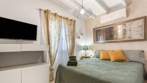 Ein Schlafzimmer mit einem Bett, einem Fernseher, einer Klimaanlage und einem Bild an der Wand.
