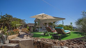 Eine Terrasse mit Liegestuhl, Sonnenschirm und Pool.