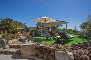 Un patio con piscina, sillas de descanso y una pérgola con sombrilla.