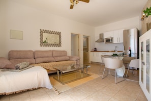 A modern living room with a sofa, coffee table, and dining area with chairs.