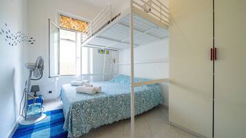 A bunk bed room with a window, a fan, and a blue checkered rug.