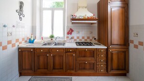 Una cocina con armarios de madera, estufa a gas, pileta y ventana.