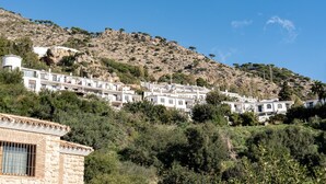 A hillside village with white buildings, a stone structure, and a clear blue sky. - Apartment 'Timón' with Sea View, Wi-Fi and Air Conditioning (Mijas)