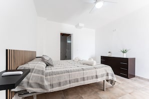 Ein modernes Schlafzimmer mit Bett, Nachttisch, Schminktisch und Deckenventilator.