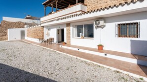 A modern house with a stone facade, a balcony, and a gravel driveway. - Apartment 'Timón' with Sea View, Wi-Fi and Air Conditioning (Mijas)