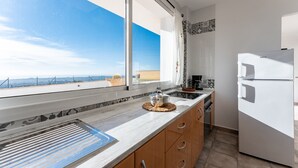 A modern kitchen with a large window, a built-in oven, and a refrigerator. - Apartment 'Timón' with Sea View, Wi-Fi and Air Conditioning (Mijas)