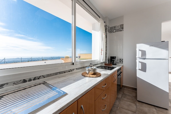 Eine moderne Küche mit großem Fenster, einem eingebauten Backofen und einem Kühlschrank.