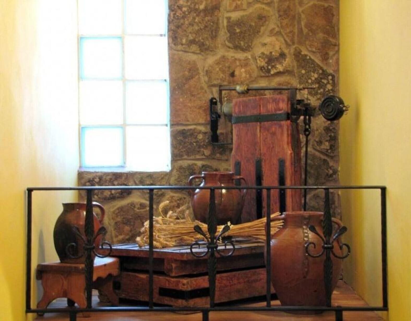 A rustic room with stone walls, a window, and a metal railing.