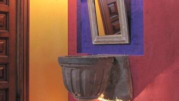 Un baño con puerta de madera, un espejo y un lavamanos empotrado.