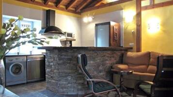 Una cocina con encimeras de piedra, horno empotrado y lavadora.