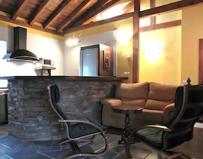 Un interior acogedor con chimenea de piedra, un sofá de cuero y dos mecedoras.