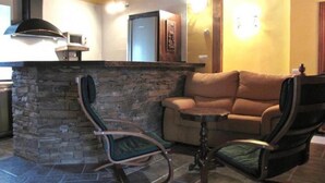 Un salón acogedor con chimenea de piedra, un sofá y dos mecedoras.