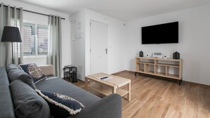 Ein modernes Wohnzimmer mit einer Couch, einem Couchtisch, einem Fernseher und einem Holzboden.