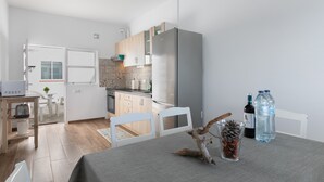 Eine moderne Küche mit Kühlschrank, Esstisch, Stühlen und einer kleinen Essecke.
