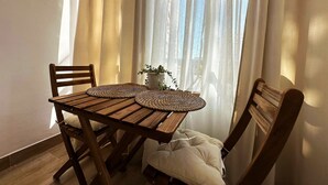 A wooden table with two woven placemats, a potted plant, and a bench with a cushion. - Studio Apartment 'Centro Torremolinos' with Shared Pool, Wi-Fi and Air Conditioning (Torremolinos)