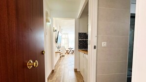 A hallway with a wooden door, a white wall, a tiled floor, a television, and a small table with chairs. - Studio Apartment 'Centro Torremolinos' with Shared Pool, Wi-Fi and Air Conditioning (Torremolinos)