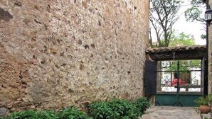 Un camí de pedra que condueix a un edifici amb una paret de pedra rústica i una porta verda.