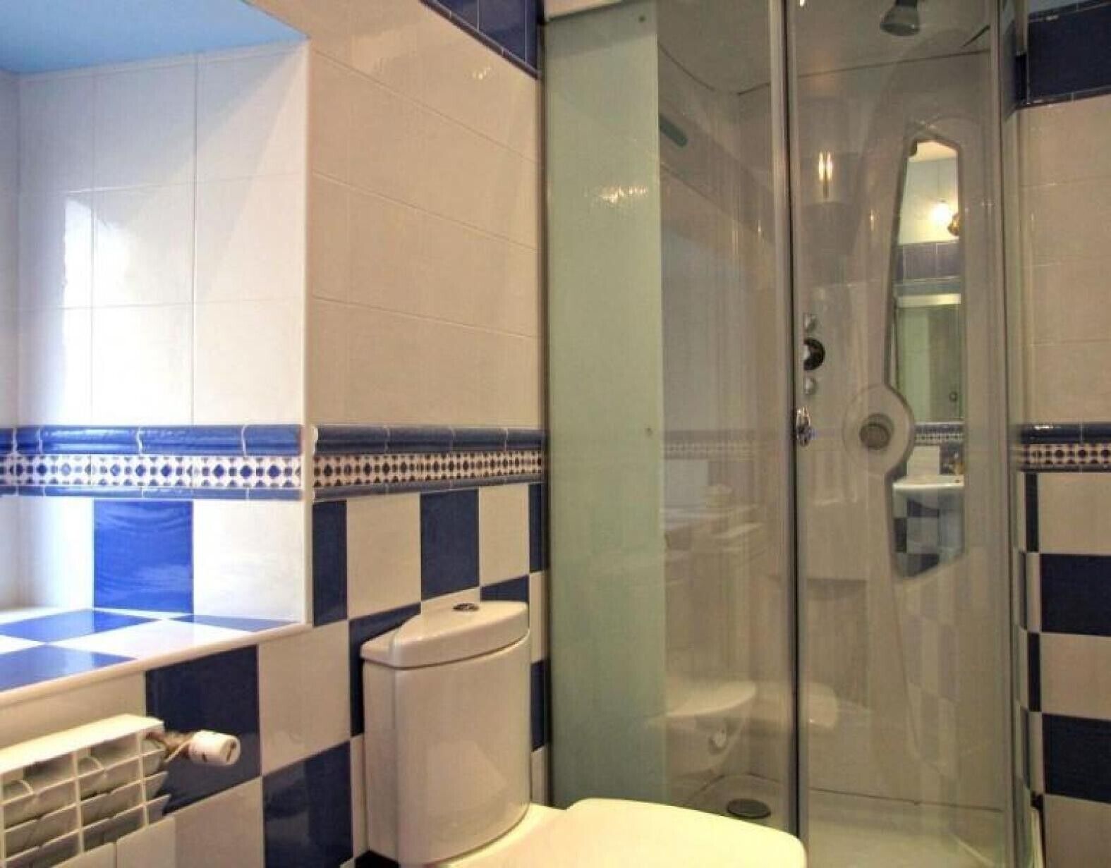 Een badkamer met toilet, wastafel en douchecabine van glas.
