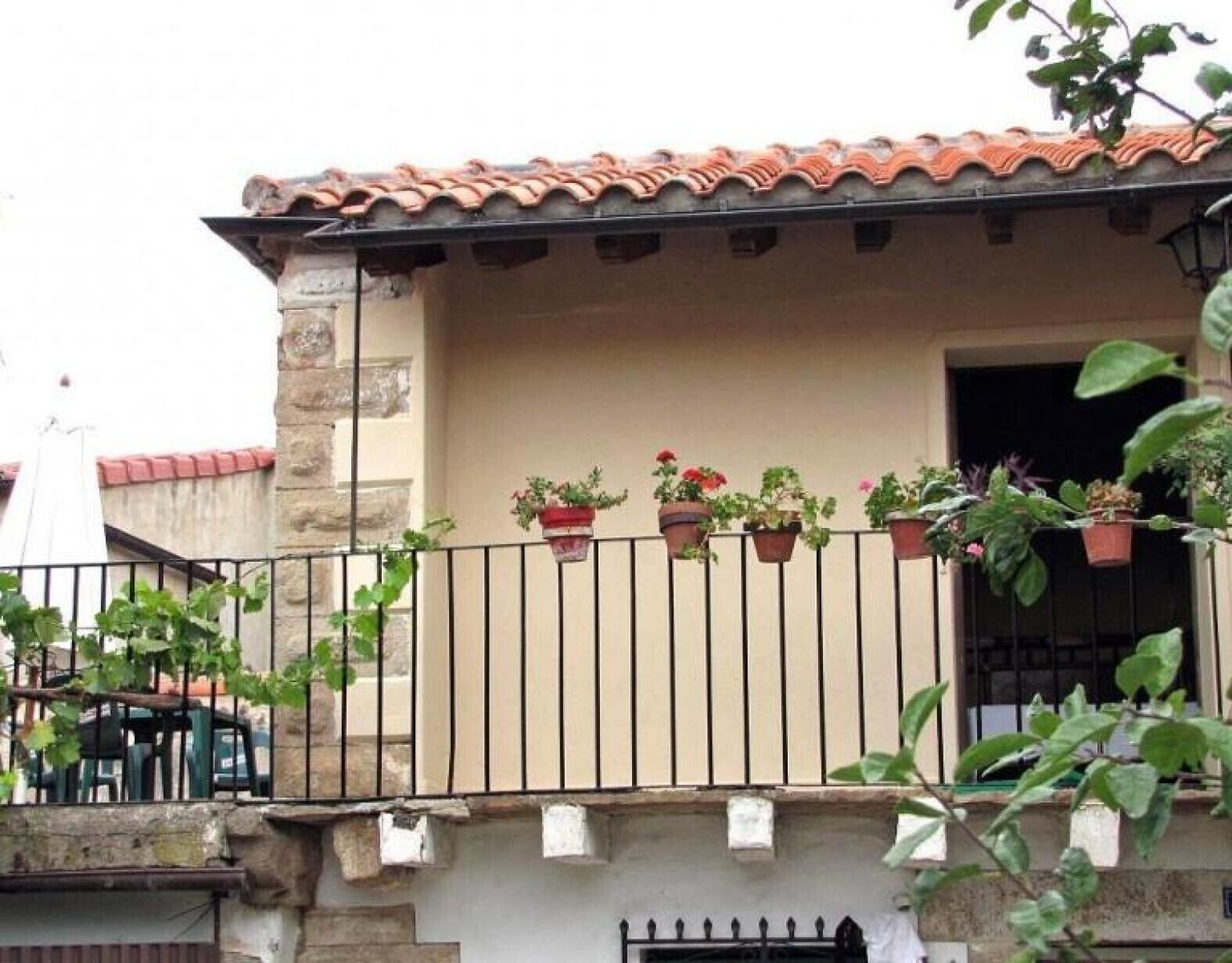 A building with a balcony, potted plants, and a stone wall.