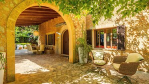 Un espace extérieur aménagé en terrasse, avec un sol en pierre, des meubles en osier et une pergola en bois.