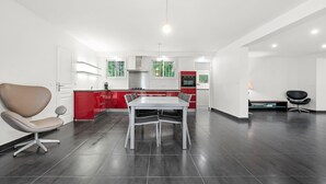 A modern kitchen with a dining area, a red accent wall, and a large window. - Villa "Stypa" with Private Pool, Wi-Fi and Air Conditioning (Trans-en-Provence)