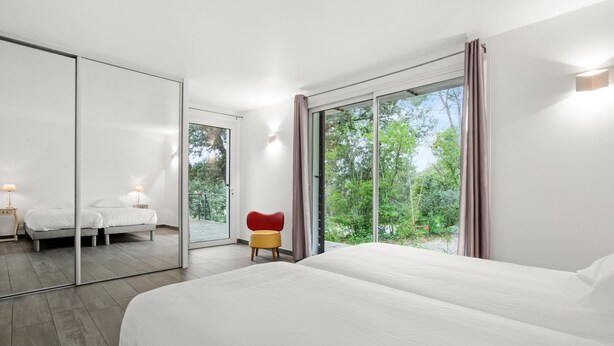 A modern hotel room with a large bed, a small seating area, a mirror, and a sliding glass door to the outdoors. - Villa "Stypa" with Private Pool, Wi-Fi and Air Conditioning (Trans-en-Provence)