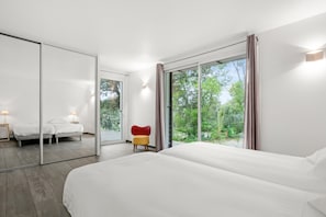 A modern hotel room with a large bed, a small seating area, a mirror, and a sliding glass door to the outdoors. - Villa "Stypa" with Private Pool, Wi-Fi and Air Conditioning (Trans-en-Provence)