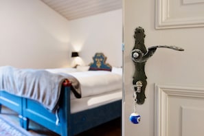 Et soveværelse med seng, natbord, lampe og en dør med et unikt håndtag.