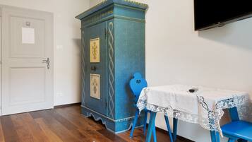 A room with a white door, a blue cabinet with decorative patterns, a table with a lace tablecloth, and blue chairs.