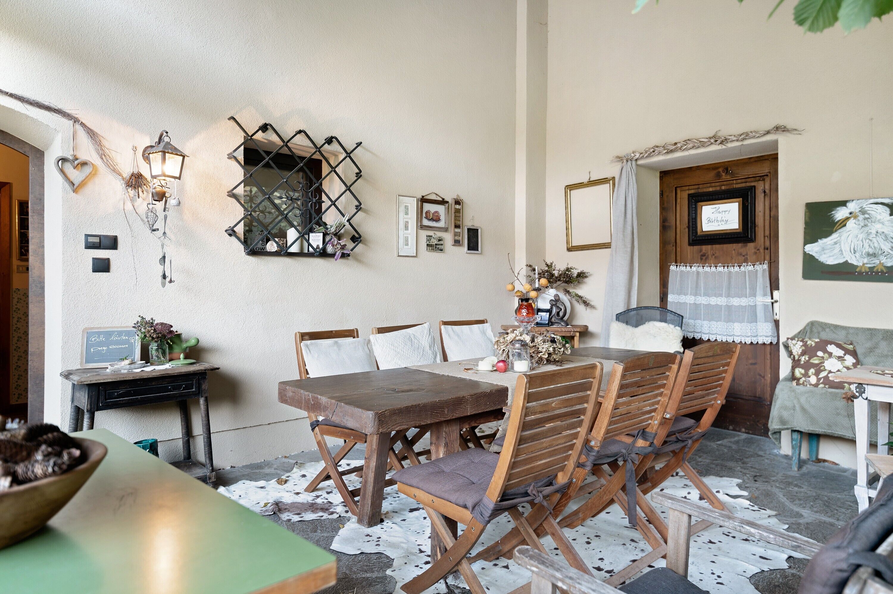 Een rustieke eethoek met een houten tafel, stoelen en een klein bijzettafeltje met een schaal.