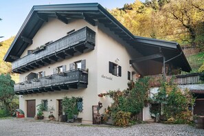 A two-story building with balconies, a gravel driveway, and surrounding vegetation. - Room 'Alter Fausthof Laika' with Mountain View, Shared Terrace and Wi-Fi (Fiè allo Sciliar)