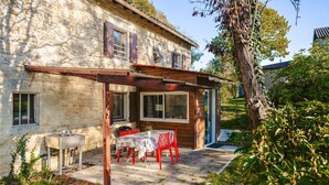 A stone building with a covered patio, a table with chairs, and a small sink.