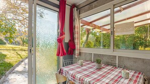 A room with a sliding glass door, a table with a plaid tablecloth, and a view of greenery outside.