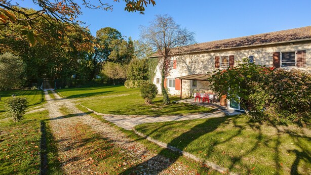 A stone building with a garden path leading to a covered area with outdoor furniture.