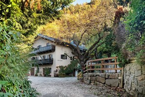 Un bâtiment avec un mur en pierre, une clôture en bois et une allée gravillonnée.