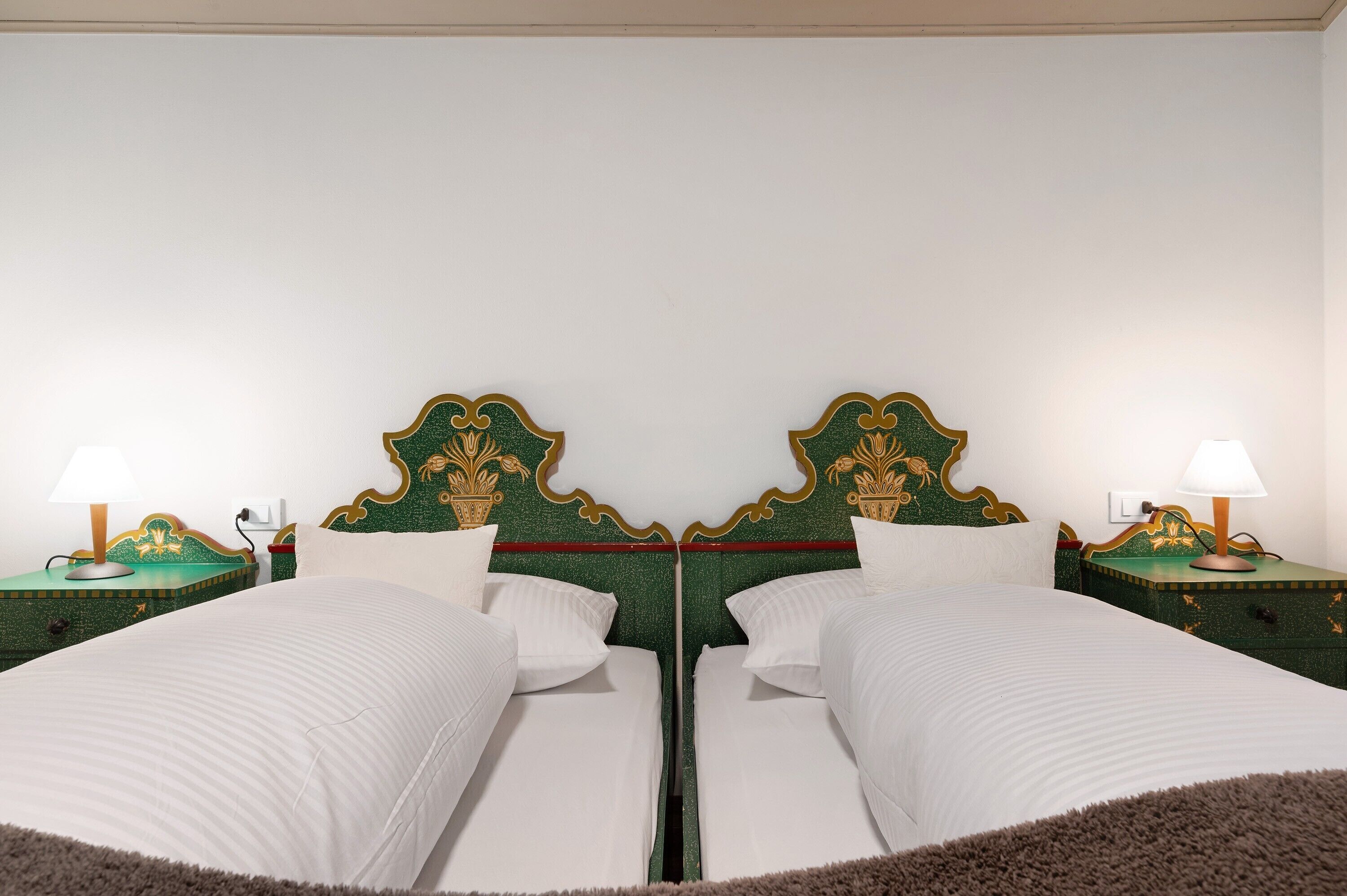 Un lit double avec une tête de lit verte, deux tables de chevet avec des lampes et du linge de lit blanc.