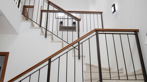 Un escalier avec des rampes en bois et des balustrades en métal, menant à l’étage supérieur.