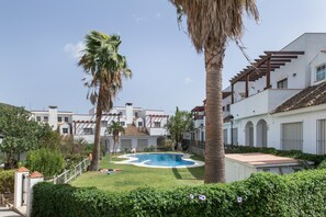 A pool surrounded by palm trees and white buildings with balconies.