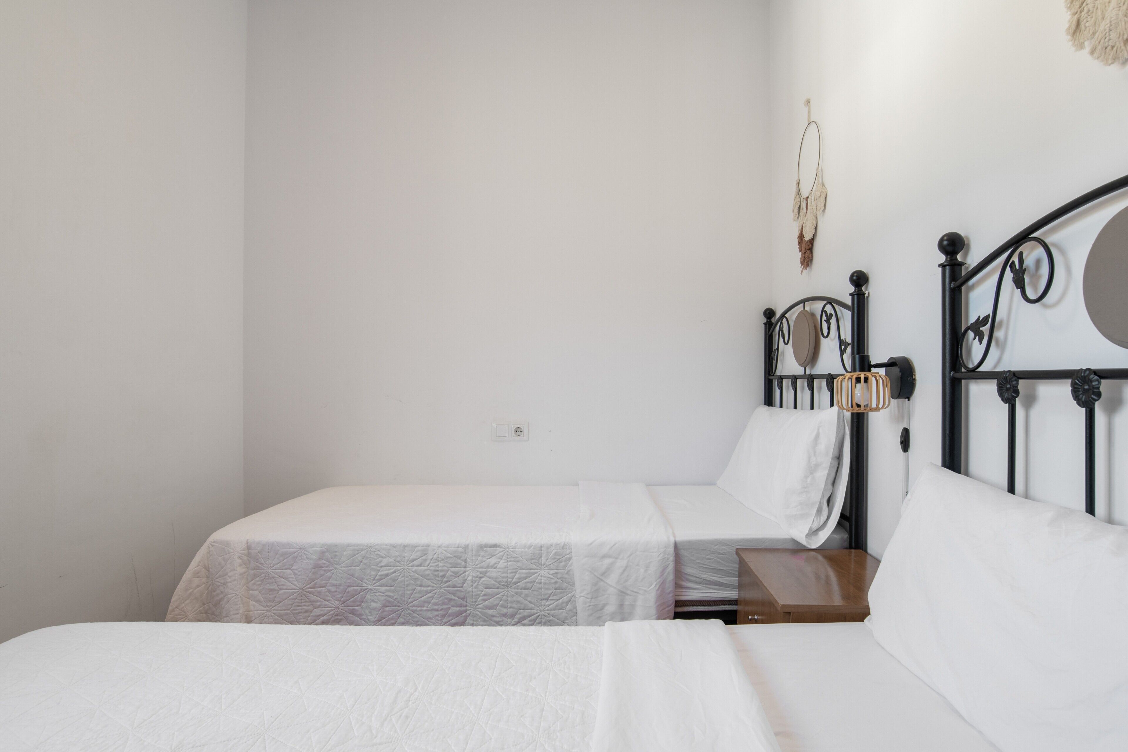 Ein Zimmer mit zwei Betten, einem Nachttisch aus Holz, einer Wandleuchte und einem dekorativen Gegenstand.